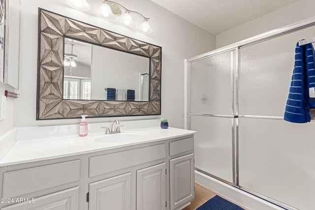 bathroom featuring hardwood / wood-style floors, vanity, a shower with door, and ceiling fan