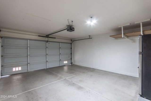 garage with a garage door opener and stainless steel refrigerator