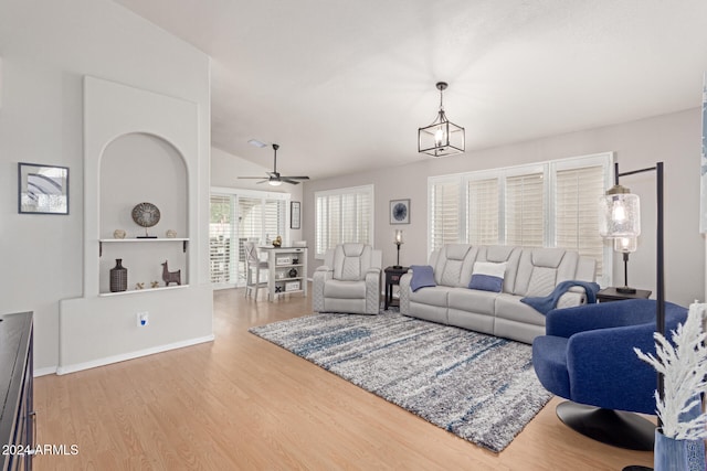 living room featuring lofted ceiling, wood-type flooring, and ceiling fan with notable chandelier