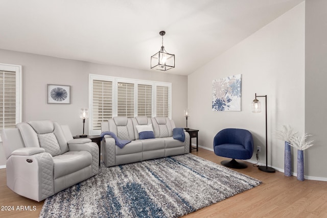 living room featuring lofted ceiling, a notable chandelier, and hardwood / wood-style flooring