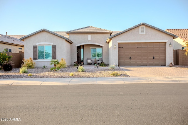 ranch-style house with decorative driveway, a garage, stucco siding, and a tiled roof