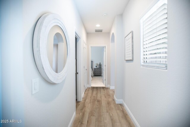 6460 W Springfield Way, Florence, AZ 85132 - corridor featuring baseboards, arched walkways, light wood finished floors, and visible vents