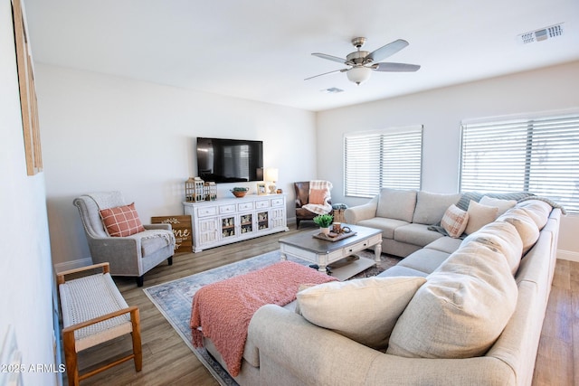 living area with visible vents, a ceiling fan, baseboards, and wood finished floors