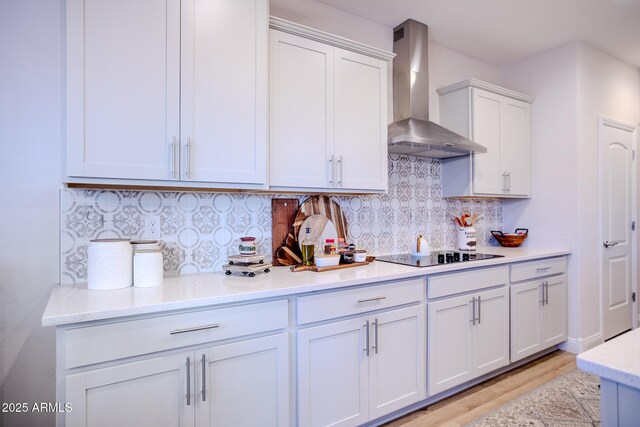 6460 W Springfield Way, Florence, AZ 85132 - kitchen with wall chimney range hood, white cabinets, black electric cooktop, light wood-type flooring, and backsplash