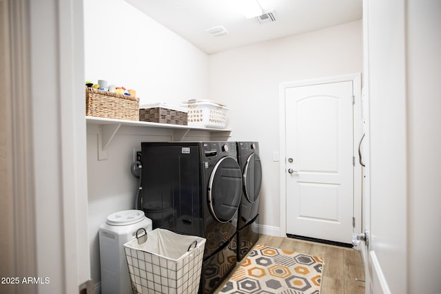 laundry area featuring laundry area, visible vents, washing machine and dryer, baseboards, and light wood finished floors