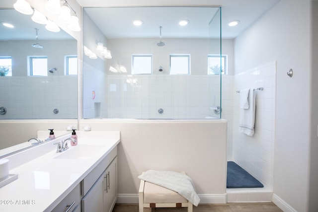 full bath featuring vanity, baseboards, and walk in shower