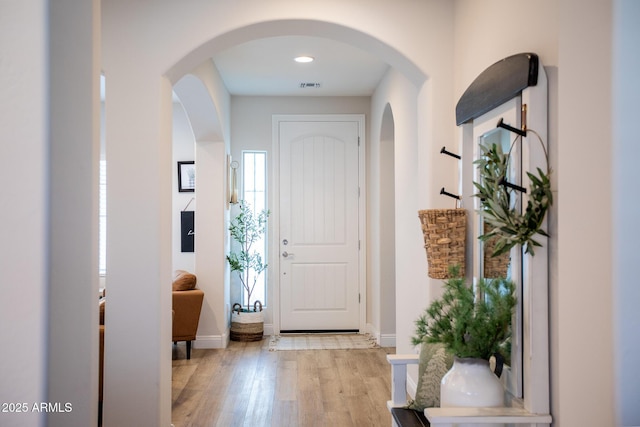 foyer entrance featuring visible vents, light wood-style flooring, baseboards, and a wealth of natural light