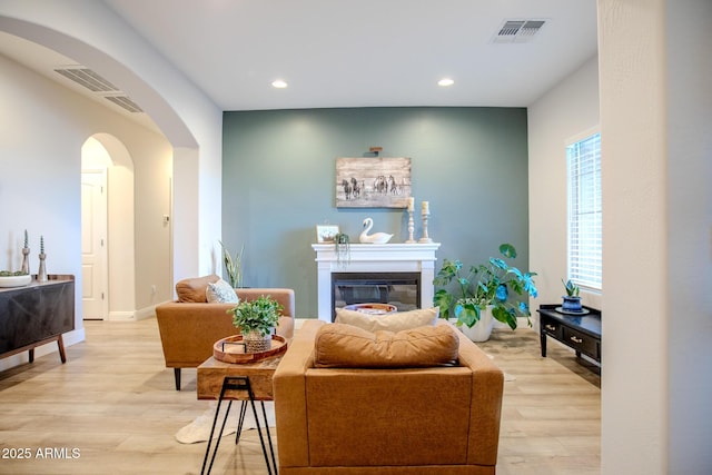 living room featuring visible vents, arched walkways, light wood-style floors, and recessed lighting