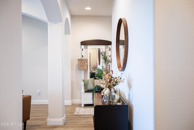 corridor featuring recessed lighting, baseboards, light wood finished floors, and arched walkways