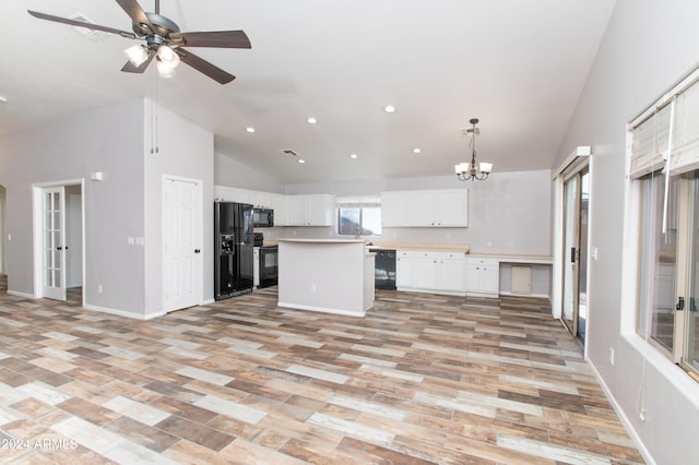 kitchen with white cabinetry, light hardwood / wood-style flooring, a kitchen island, black appliances, and ceiling fan with notable chandelier