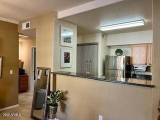 kitchen with light brown cabinets, light tile patterned floors, and stainless steel refrigerator