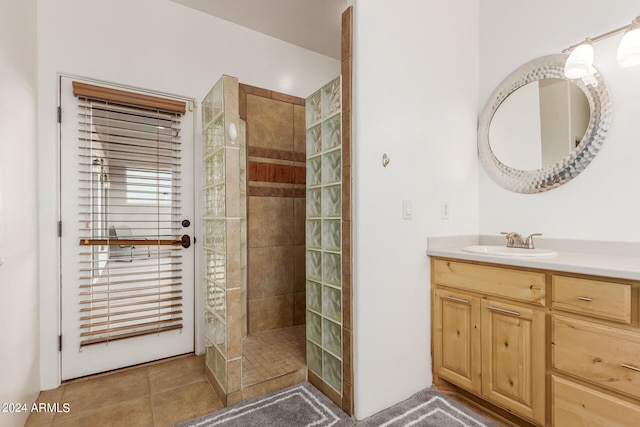 bathroom featuring vanity, a tile shower, and tile flooring