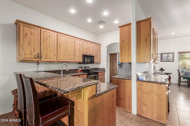 kitchen with a kitchen breakfast bar, light tile flooring, kitchen peninsula, dark stone counters, and stainless steel range with electric cooktop