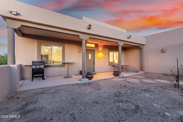 back house at dusk with a patio area