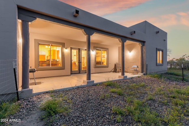 back house at dusk featuring a patio