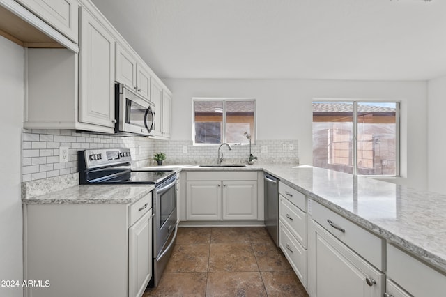 kitchen with sink, appliances with stainless steel finishes, white cabinets, and plenty of natural light