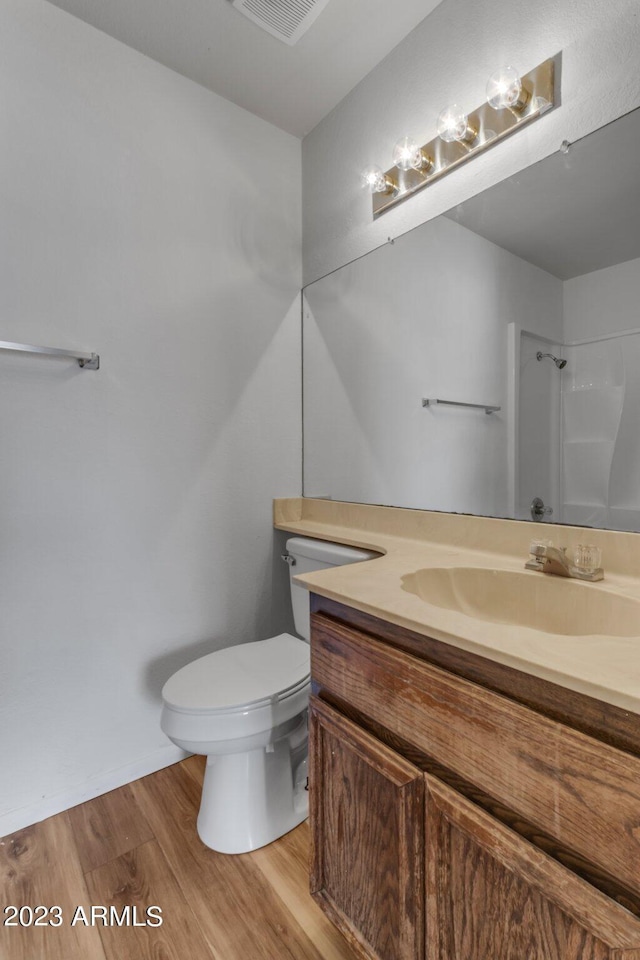 bathroom featuring a shower, hardwood / wood-style floors, vanity, and toilet