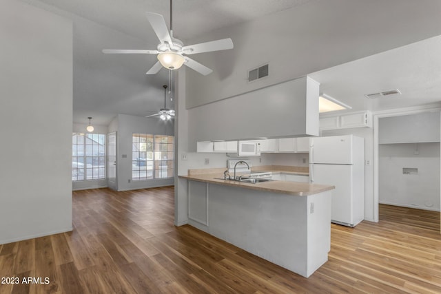 kitchen featuring kitchen peninsula, white appliances, sink, hardwood / wood-style flooring, and white cabinets