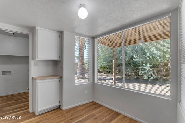 unfurnished dining area with a textured ceiling, light wood-type flooring, and plenty of natural light