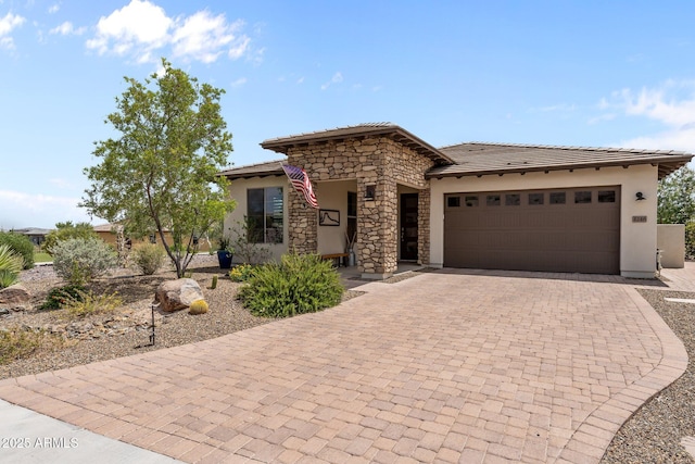 4246 Stage Stop Way, Wickenburg, AZ 85390 - view of front of home featuring decorative driveway, stucco siding, an attached garage, a tiled roof, and stone siding