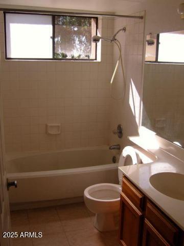 full bathroom featuring tile patterned flooring, tiled shower / bath, plenty of natural light, and toilet