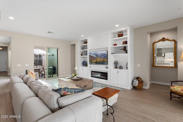 living room with light wood-type flooring and built in features