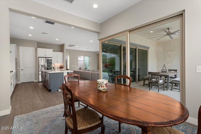 dining space with wood-type flooring, ceiling fan, and sink