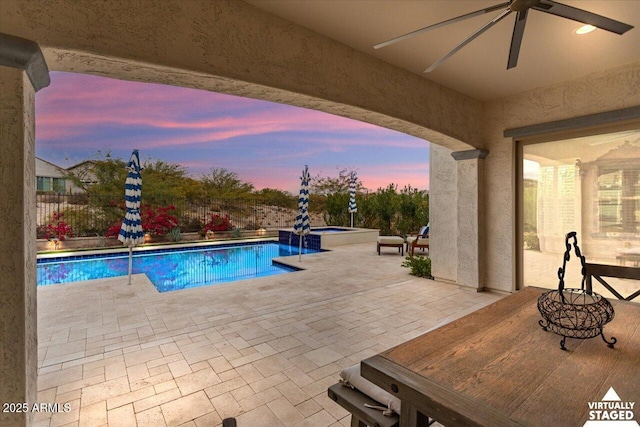 pool at dusk featuring a patio area and ceiling fan