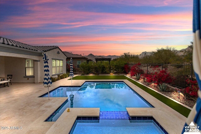 pool at dusk with an in ground hot tub