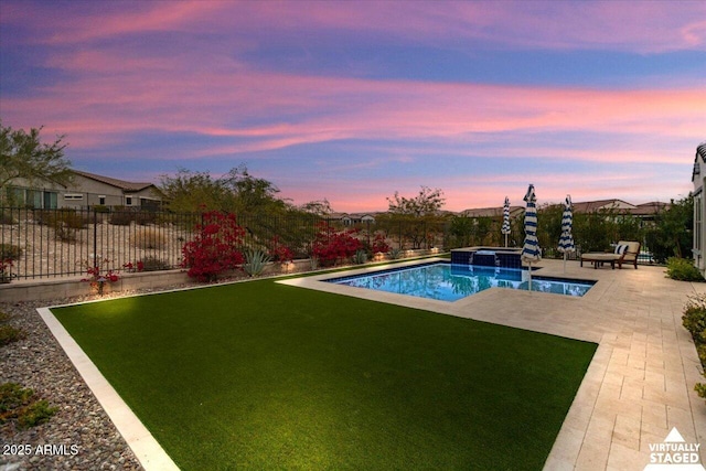 pool at dusk featuring a lawn and a patio area