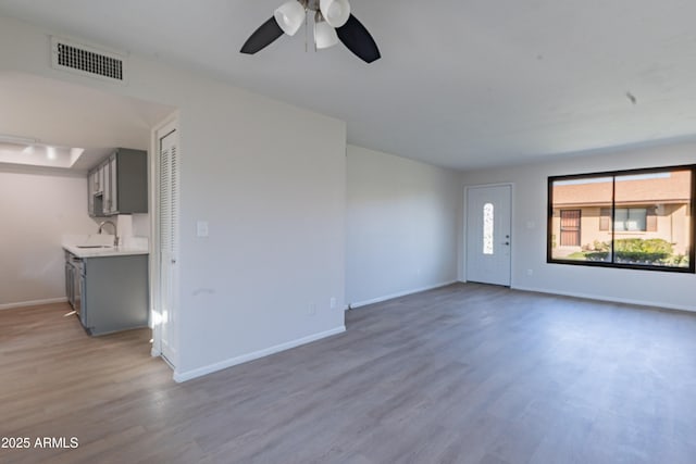2440 N 22nd Ave, Phoenix, AZ 85009 - unfurnished living room with a sink, wood finished floors, ceiling fan, and baseboards