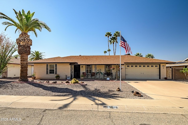 ranch-style home featuring a shingled roof, an attached garage, covered porch, concrete driveway, and brick siding