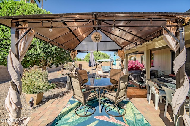 view of patio with a gazebo, outdoor dining area, and fence