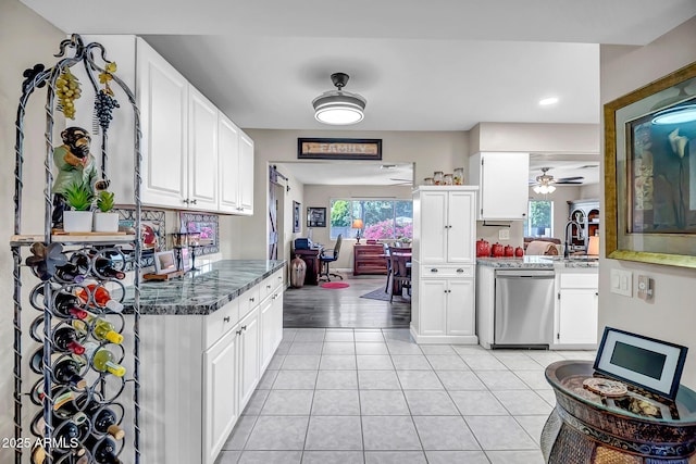 kitchen featuring light tile patterned flooring, a healthy amount of sunlight, dishwasher, and white cabinets