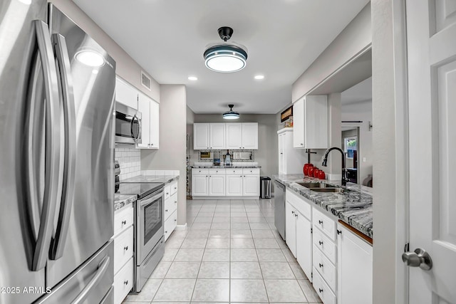 kitchen featuring white cabinets, light tile patterned floors, a sink, and appliances with stainless steel finishes