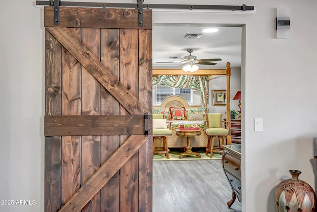 interior space featuring a barn door, visible vents, and wood finished floors