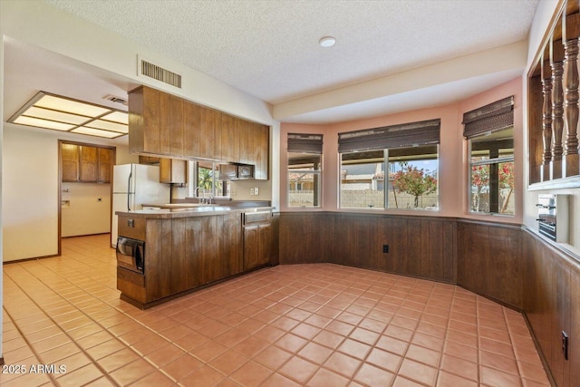 kitchen with visible vents, freestanding refrigerator, a peninsula, and black microwave