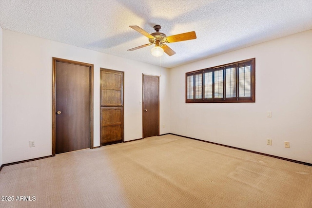 unfurnished bedroom featuring baseboards, a textured ceiling, multiple closets, and carpet floors