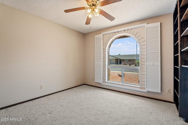 carpeted spare room featuring a textured ceiling, ceiling fan, and baseboards