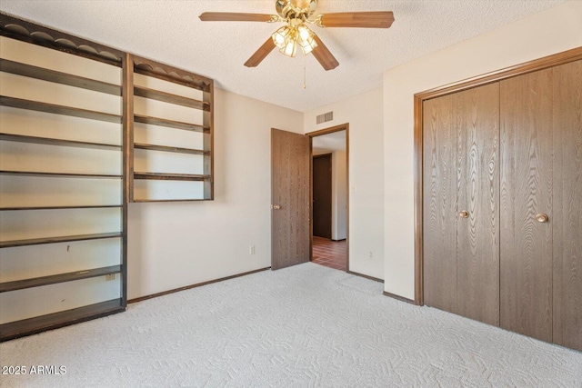 unfurnished bedroom featuring carpet flooring, ceiling fan, a textured ceiling, baseboards, and visible vents