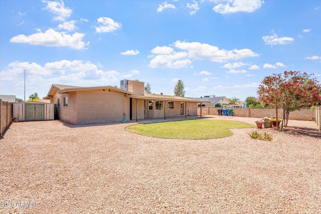 rear view of property featuring a patio area, an outdoor structure, a fenced backyard, a storage unit, and stucco siding