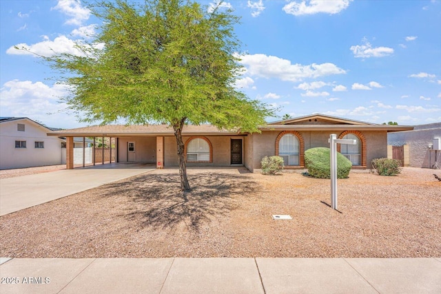 ranch-style home featuring fence, a carport, and driveway
