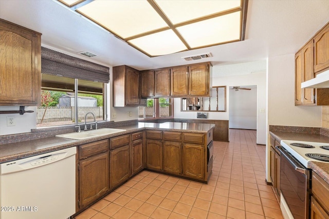 kitchen with visible vents, a sink, dark countertops, and white appliances