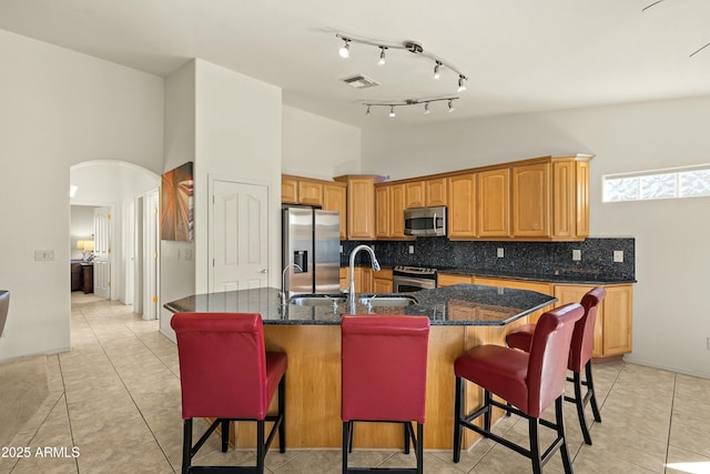 kitchen with a breakfast bar, sink, decorative backsplash, a kitchen island with sink, and stainless steel appliances