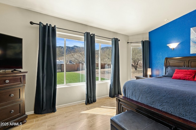 bedroom featuring multiple windows, a mountain view, and light hardwood / wood-style floors