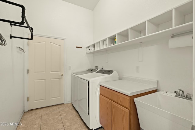 clothes washing area featuring sink, light tile patterned floors, cabinets, and washer and dryer