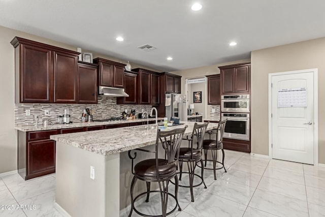 kitchen with visible vents, a kitchen breakfast bar, marble finish floor, stainless steel appliances, and a sink