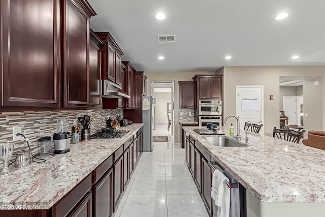 kitchen with visible vents, under cabinet range hood, marble finish floor, stainless steel appliances, and a sink