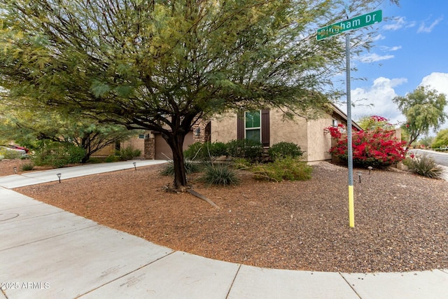 obstructed view of property featuring concrete driveway and stucco siding