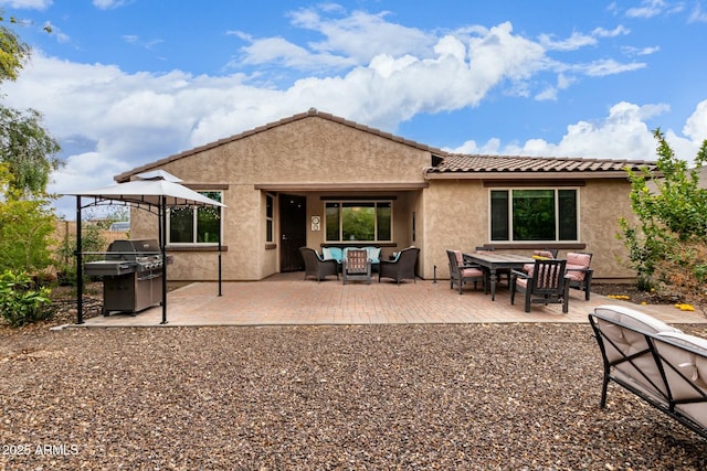 rear view of property featuring a patio area, outdoor dining space, stucco siding, and a tiled roof